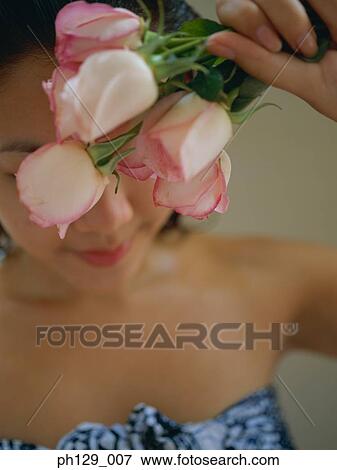 Stock Photo - Woman holding stalks of roses, smiling. Fotosearch