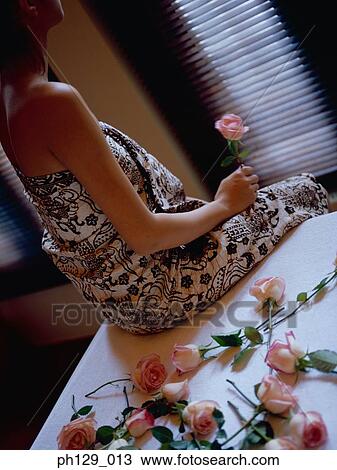 Woman in robe, holding a stalk of rose View Large Photo Image Stock Image - Woman in robe, holding a stalk of rose. Fotosearch