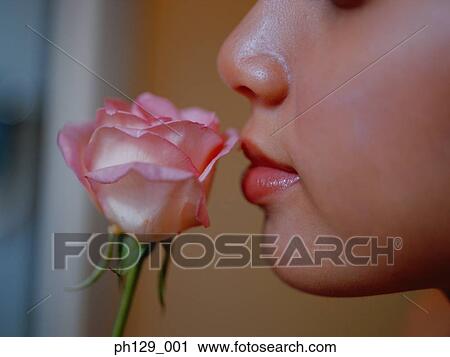 Stock Image - Woman sniffing rose, close-up. Fotosearch