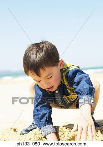 Young boy digging in sand View Large Photo Image Stock Image - Young boy digging in sand. Fotosearch