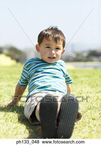 Young boy lying on the grass View Large Photo Image Stock Photo - Young boy lying on the grass. Fotosearch