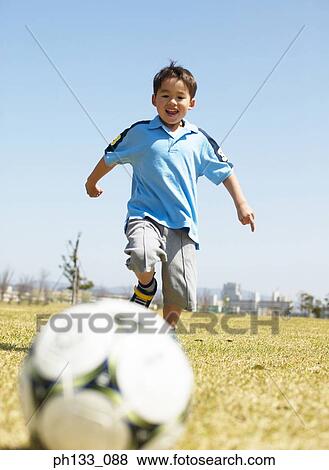 Stock Photo - Young boy playing football. Fotosearch