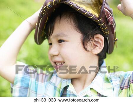Stock Image - Young boy smiling with baseball mitt over head. Fotosearch