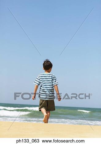 Young boy walking on beach View Large Photo Image Stock Image - Young boy walking on beach. Fotosearch