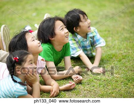 Stock Image - Young children lying down looking up and smiling. Fotosearch