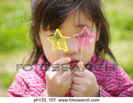 Stock Photo - Young girl holding two lollipops. Fotosearch