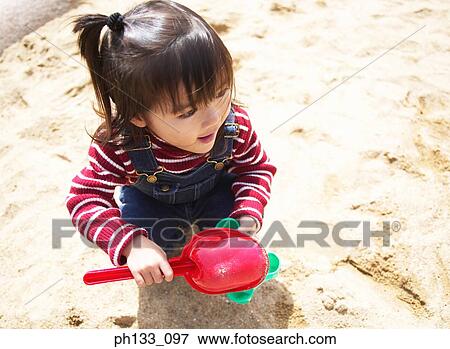Young girl playing in sandpit View Large Photo Image Stock Photo - Young girl playing in sandpit. Fotosearch