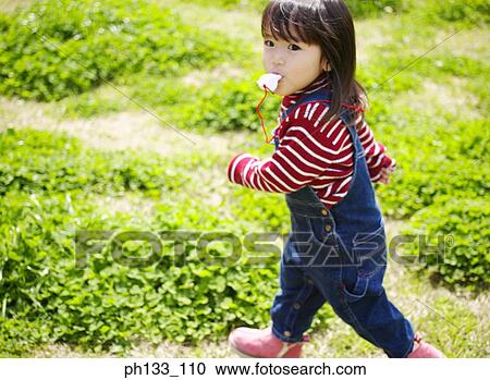 Stock Image - Young girl walking with pacifier in her mouth. Fotosearch