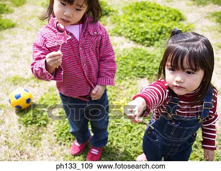 Young girls standing holding lollipops View Large Photo Image Stock Photo - Young girls standing holding lollipops. Fotosearch