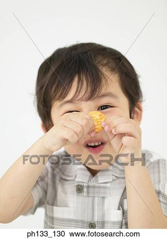 Stock Image - Young boy holding up a biscuit. Fotosearch