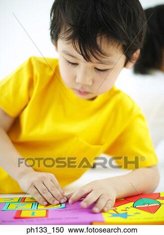Stock Image - Young boy playing jigsaw puzzle. Fotosearch