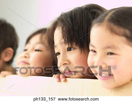 Young children peeping over a cardboard partition and smiling View Large Photo Image Stock Photo - Young children peeping over a cardboard partition and smiling. Fotosearch