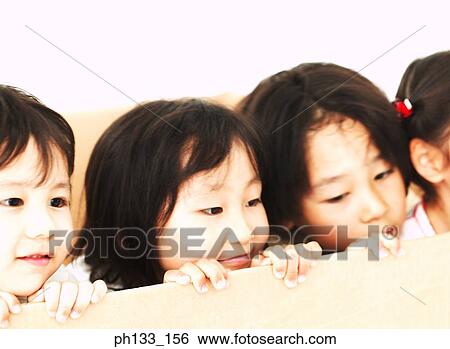 Stock Photograph - Young children peeping over a cardboard partition and smiling. Fotosearch