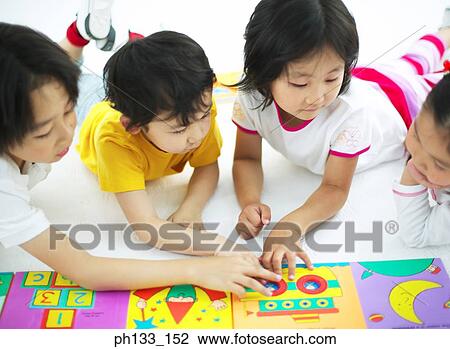 Stock Image - Young children playing with jigsaw puzzle. Fotosearch