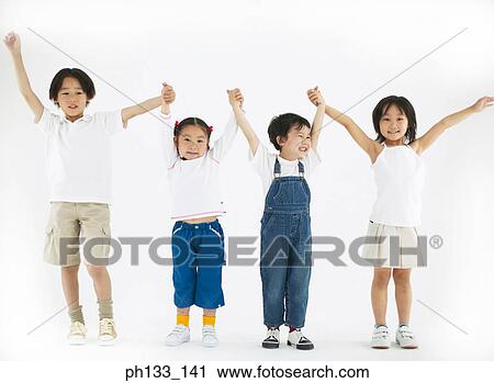Stock Image - Young children standing with their hands raised. Fotosearch