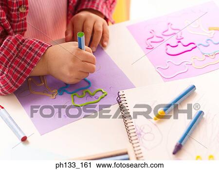 Stock Image - Young girl drawing with animal stencils. Fotosearch