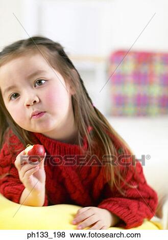 Young girl eating fruit View Large Photo Image Stock Photo - Young girl eating fruit. Fotosearch