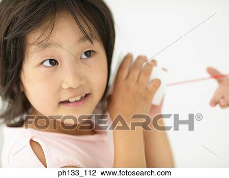 Young girl holding a cup with a string up to her ear View Large Photo Image Stock Image - Young girl holding a cup with a string up to her ear. Fotosearch