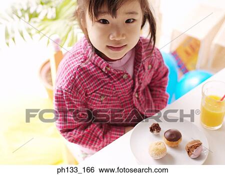 Young girl seated at a table looking up View Large Photo Image Stock Photograph - Young girl seated at a table looking up. Fotosearch