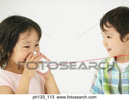 Stock Image - Young girl smiling & talking on toy telephone. Fotosearch