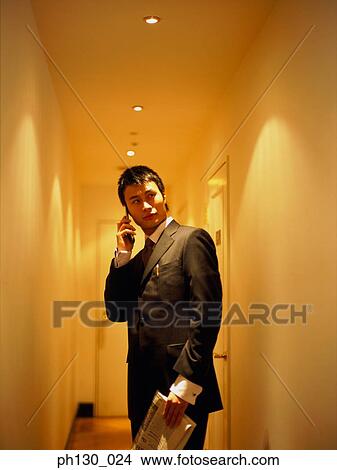 Picture - Asian Man answering a cell phone. Fotosearch