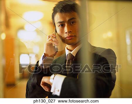 Asian Man answering a cell phone View Large Photo Image Stock Photo - Asian Man answering a cell phone. Fotosearch