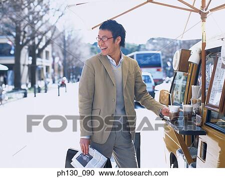 Stock Image - Asian Man buying coffee from a vendor. Fotosearch