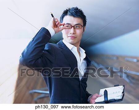 Asian Man distracted from work View Large Photo Image Stock Photo - Asian Man distracted from work. Fotosearch