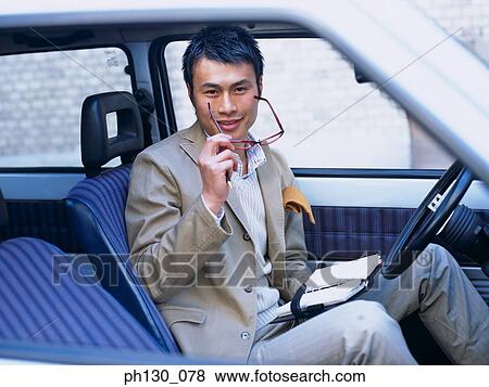 Asian Man in a car taking his spectacles off View Large Photo Image Stock Photo - Asian Man in a car taking his spectacles off. Fotosearch