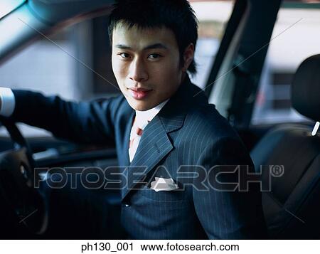 Stock Image - Asian Man in the drivers seat of a car. Fotosearch