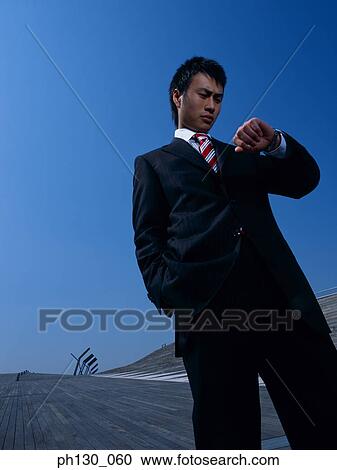 Stock Image - Asian Man looking at the time. Fotosearch