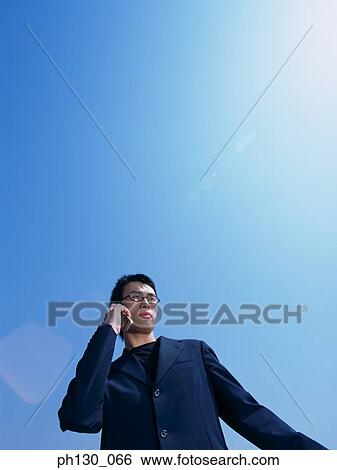 Asian Man talking on a cell phone View Large Photo Image Stock Photograph - Asian Man talking on a cell phone. Fotosearch