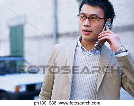Asian Man using his cell phone View Large Photo Image Stock Photograph - Asian Man using his cell phone. Fotosearch