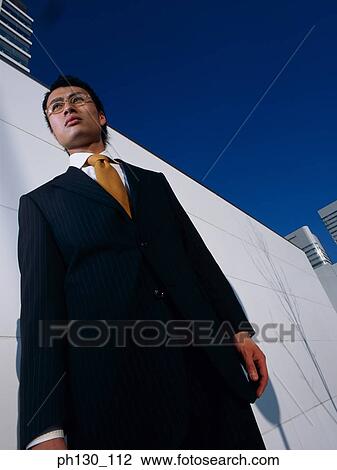 Stock Image - Asian Standing amidst skyscrapers. Fotosearch