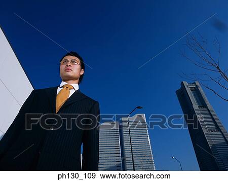 Asian Standing amidst skyscrapers View Large Photo Image Stock Photo - Asian Standing amidst skyscrapers. Fotosearch