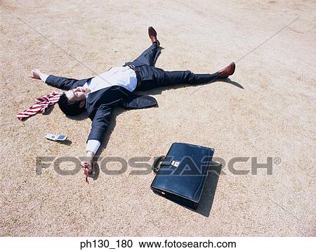 Stock Image - Asian Businessman lying flat on the ground. Fotosearch