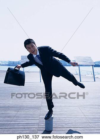 Stock Photo - Asian Man balancing on a pipe head. Fotosearch