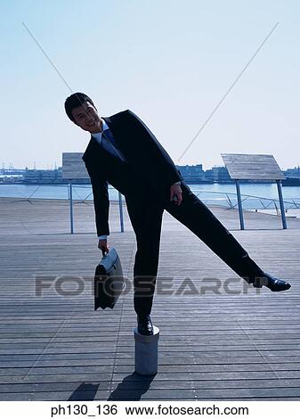 Asian Man balancing on a pipe head View Large Photo Image Stock Photograph - Asian Man balancing on a pipe head. Fotosearch