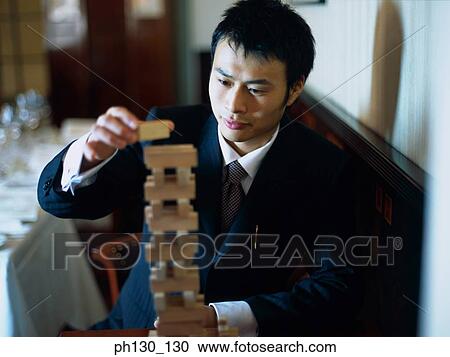 Stock Image - Asian Man making a tower of blocks. Fotosearch