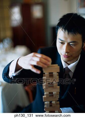 Stock Image - Asian Man making a tower of blocks. Fotosearch