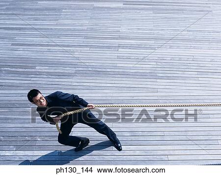 Picture - Asian Man pulling at a rope. Fotosearch