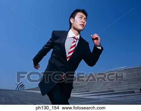 Picture - Asian Man running down a bridge. Fotosearch