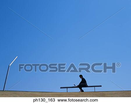 Stock Image - Asian Man sitting and working on his laptop. Fotosearch