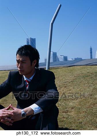 Asian Man sitting on a grassy slope View Large Photo Image Stock Image - Asian Man sitting on a grassy slope. Fotosearch