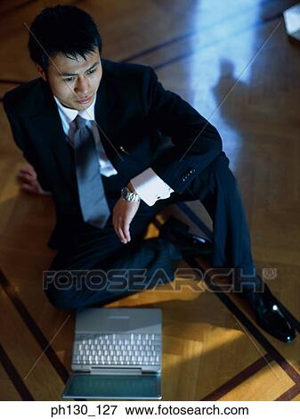 Asian Man sitting on the floor with a laptop View Large Photo Image Stock Photo - Asian Man sitting on the floor with a laptop. Fotosearch