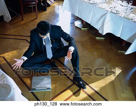 Asian Man sitting on the floor with a laptop View Large Photo Image Stock Photo - Asian Man sitting on the floor with a laptop. Fotosearch