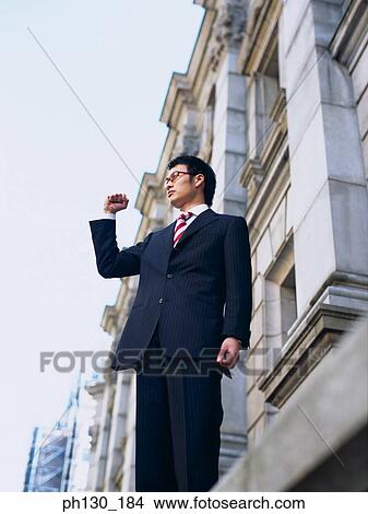 Picture - Asian Man standing on a ledge. Fotosearch