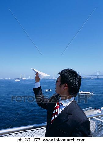 Stock Photo - Asian Man throwing a paper plane overboard. Fotosearch
