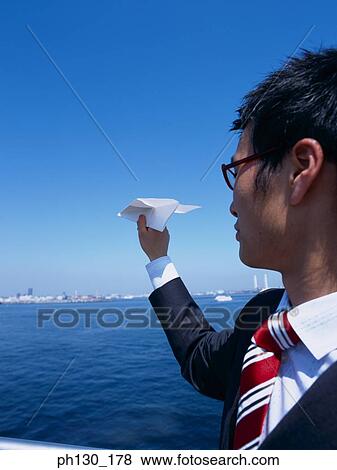 Stock Photo - Asian Man throwing a paper plane overboard. Fotosearch