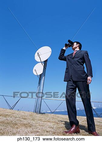 Man at an installation looking through binoculars View Large Photo Image Stock Image - Man at an installation looking through binoculars. Fotosearch